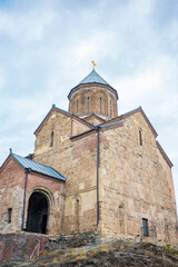 Naklejka premium Close-up view of an ancient Georgian Orthodox stone church in Tbilisi, Georgia. With its detailed brickwork, arched entrance, cross-topped dome, the historic structure and spiritual heritage