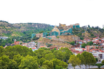 Panoramic view of Narikala Fortress with its historic church perched on a hillside above Tbilisi,...