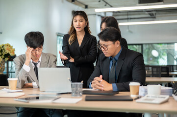 Serious businesswoman frown talking while man coworkers looking at laptop on wooden table in office.