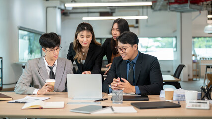 Smiling businesswoman pointing at laptop talk or explain to coworker at wooden table in meeting room