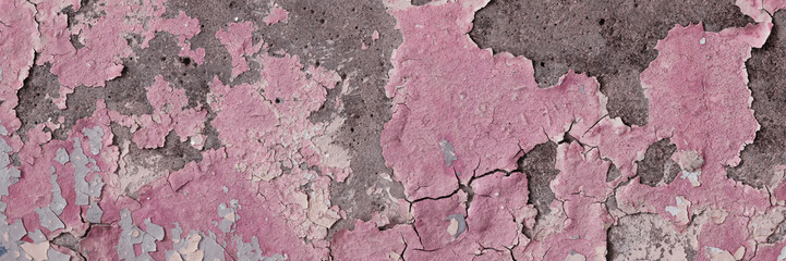 Peeling paint on the wall. Panorama of a concrete wall with old cracked flaking paint. Weathered rough painted surface with patterns of cracks and peeling. Wide panoramic grunge texture for background