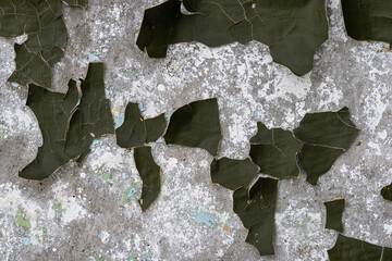 Peeling paint on the wall. Old concrete wall with cracked flaking paint. Weathered rough painted surface with patterns of cracks and peeling. Grunge texture for background and design. High resolution.