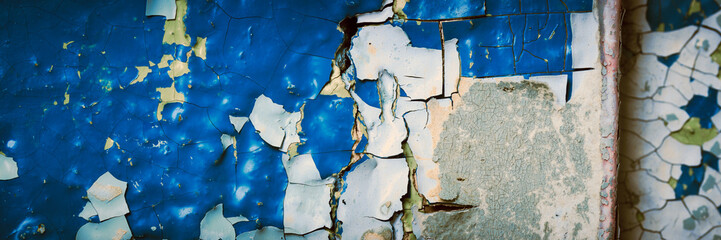 Peeling paint on the wall. Panorama of a concrete wall with old cracked flaking paint. Weathered rough painted surface with patterns of cracks and peeling. Wide panoramic texture for grunge background