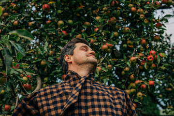 stylish European man in a vintage brown wool blazer stands contemplatively by an apple tree