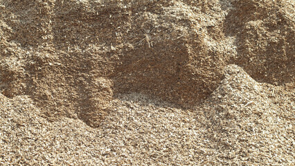 mountains of wood chips against the blue sky and green forest
