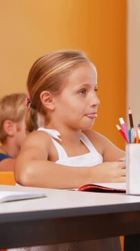 Animation of school icons over diverse schoolchildren in classroom