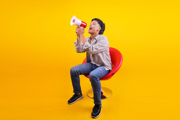Full Length Of Energetic Young Asian Male With Megaphone While Seated In Stylish Chair