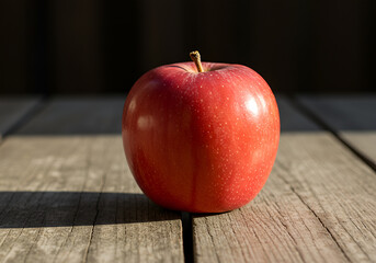 Fresh red apple on rustic wooden table with natural sunlight and detailed texture