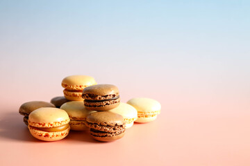 Pile of brown and beige macaroons on pastel gradient background