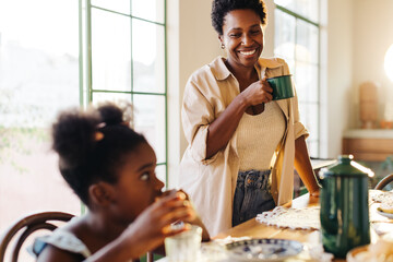 Happy mom enjoying breakfast with her daughter, sipping on café coado