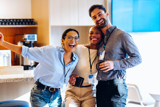 Group of colleagues smiling together during a casual break in the office - Powered by Adobe
