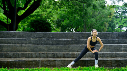 Young woman stretching legs outdoors on stone step in an open-air urban park environment