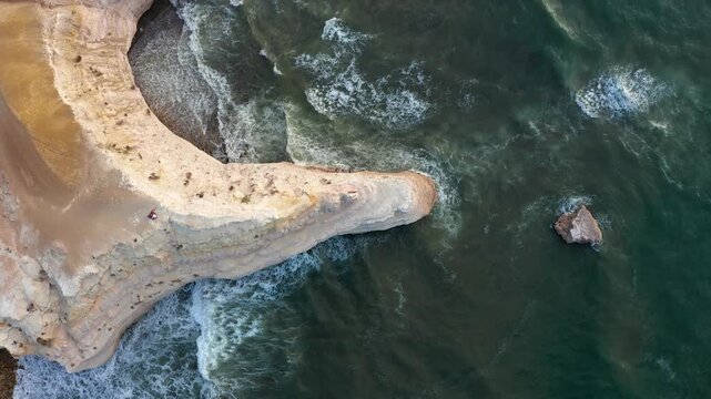 Aerial top down view of Blanche Point cliff and crashing waves with couple sitting on edge, Port Willunga, Adelaide, South Australia