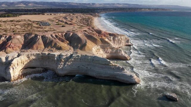 Drone reverse shot reveals Blanche Point cliffs with people sitting on edge, Port Willunga, Adelaide, South Australia