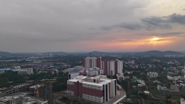 An aerial video of a mixed urban landscape. The scene includes completed modern buildings, an ongoing construction site, and a natural lake, illustrating the rapid growth of a city. VIT Chennai