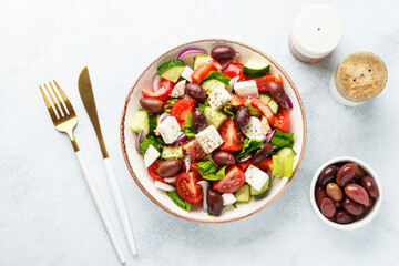 Greek salad in craft plate on white kitchen table.