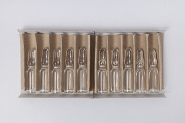 Top view of row of ampoules in cardboard pack on white clean background
