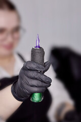 Girl holding a tattoo machine in her hand