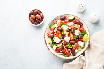 Greek salad in craft plate on white kitchen table.