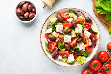 Greek salad in craft plate on white kitchen table.