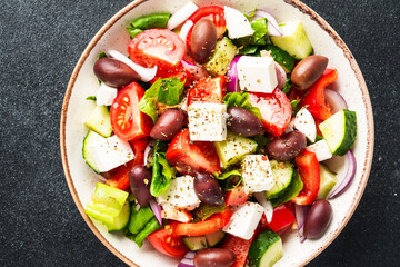 Greek salad in craft plate on black kitchen table.