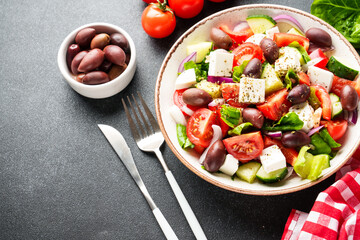 Greek salad in craft plate on black kitchen table.