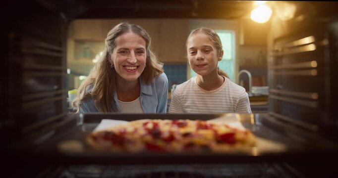 Mother and Daughter Open the Oven, Revealing a Delicious Homemade Pizza. They Smile withJoy and Anticipation in the Cozy Kitchen Setting. Point of View Pov From Inside Oven.