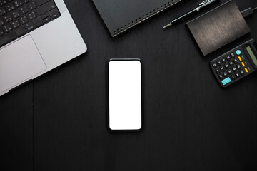 Top View Work space office desk, mockup empty screen smartphone on black wooden table. with clipping path, with blank space screen for advertising text