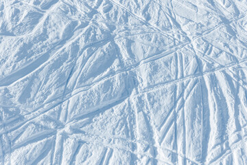 Snowy abstract off-piste skiing background with ski and snowboard trails and tracks on new virgin powder snow. morning sunrise or evening sunset time at alpine mountain resort