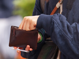 Midsection of a person holding a brown wallet and taking out money while shopping at Naplavka farmers market in Prague.