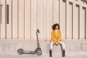 Afro woman relaxing with electric scooter after work commute,sustainable urban transportation