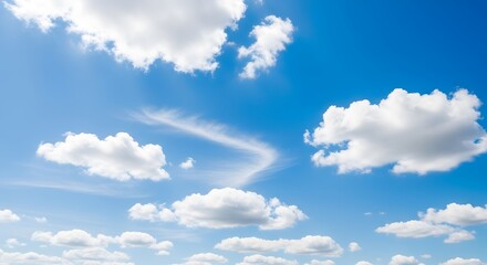 Obraz premium Fluffy white cumulus clouds drift across a vibrant blue sky on a clear sunny day, with a wispy cirrus cloud formation in the distance