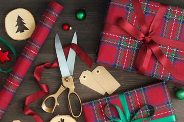 Preparing for Christmas. A flat lay photograph of Christmas gift wrapping supplies on a dark wooden surface. Red and green colors.