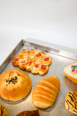 Close up of tomato cheese bread and assorted bakery rolls on tray