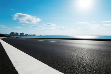 A smooth asphalt road with a clear blue sky and sea in the distance