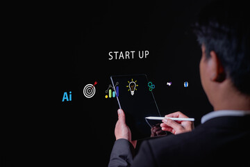 Businessman holding digital tablet with startup icons including AI, target, analytics, innovation, and teamwork, representing technology, entrepreneurship business growth.