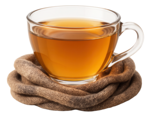 Glass teacup of chamomile tea resting on folded woolen scarf in muted earth tones