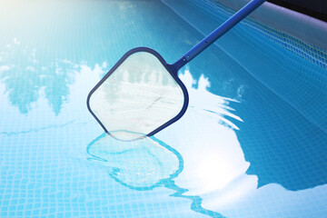 Cleaning swimming pool with skimmer net, closeup