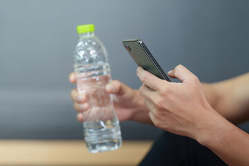 Modern Lifestyle. Young man holding a water bottle and smartphone, promoting wellness.