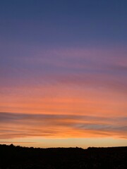 Obraz premium Beautiful colorful sunset sky with vibrant orange and purple clouds above dark forest silhouette