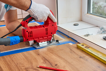 repairman using electric jigsaw and cutting hole for the sink in the kitchen countertops