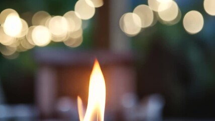 Close up of a candle flame with bokeh lights in the background. - Powered by Adobe
