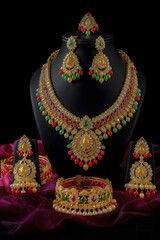 Exquisite gold jewelry set with necklace, earrings, bangles, and bracelet adorned with colorful gemstones and pearls, showcasing traditional Indian craftsmanship, elegance, and festive luxury.