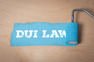 Concept of DUI law with paint roller applying blue paint on wooden surface. Legal system, driving...
