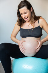 Pregnant woman experiencing contractions while sitting on exercise ball