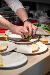Male chef adds greens on bruschetta in restaurant kitchen