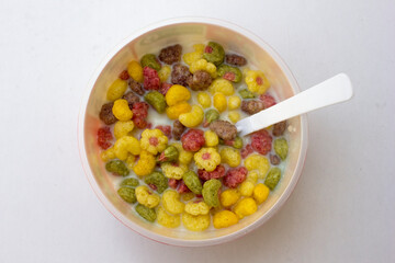 A bowl of colorful cereals with milk isolated on white background.