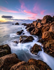 Obraz premium Rocky shoreline at sunset. Ocean waves moving through rocks