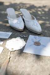 Elegant wedding day still life with bridal shoes, rings, and stationery on a stone surface