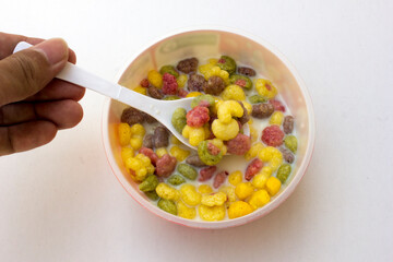 A bowl of colorful cereals with milk isolated on white background.